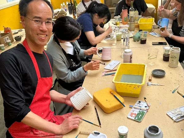 Pottery painting team-building workshop in San Francisco with brushes and glazed ceramics.
