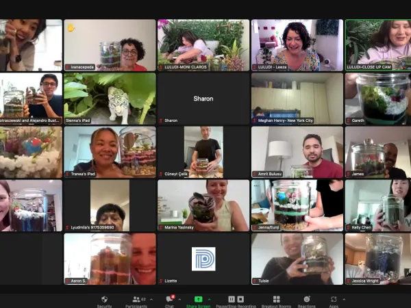 Virtual terrarium workshop for remote teams with participants holding completed terrariums on video call.