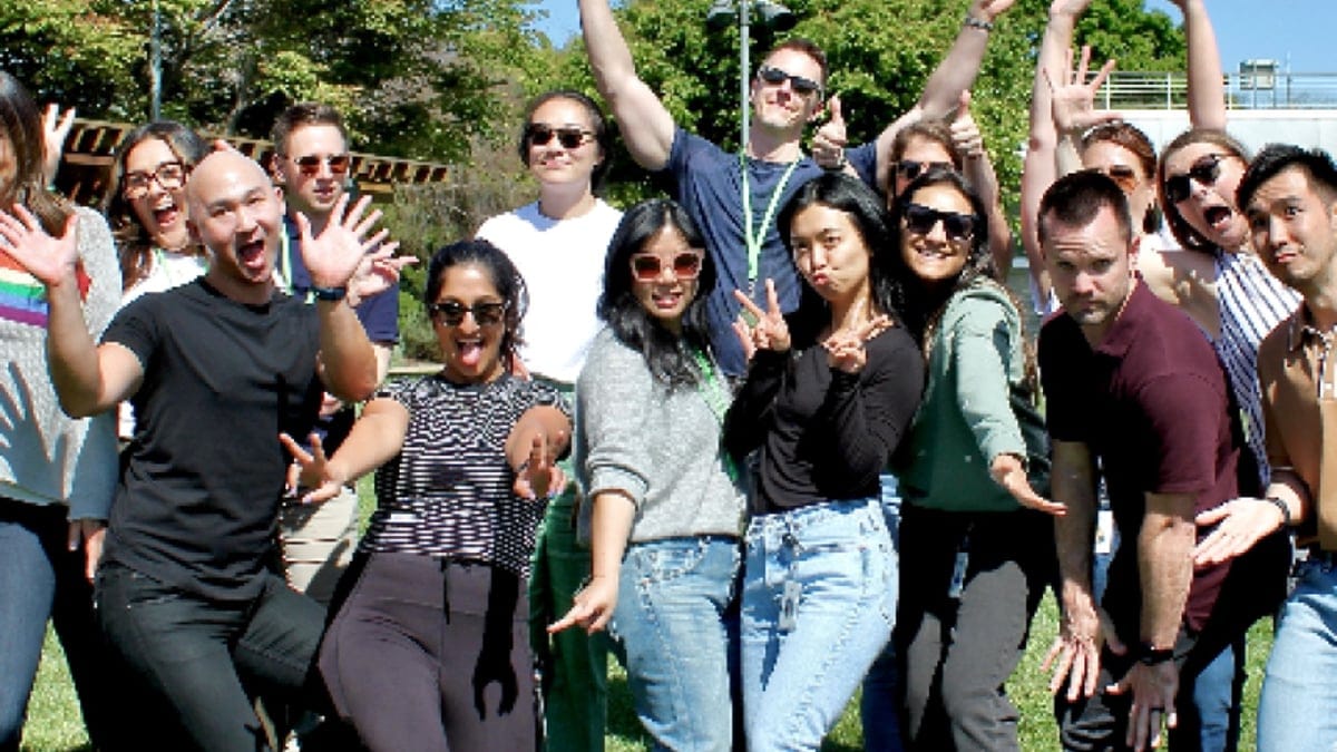 A large corporate team laughing and posing together outdoors during a team building game