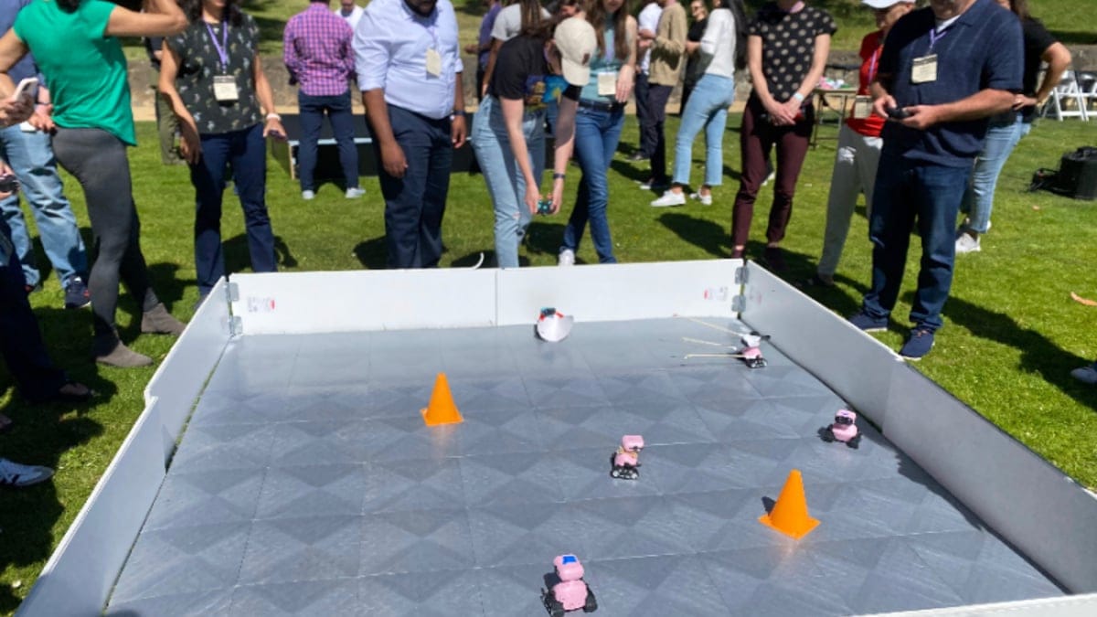 Biotech professionals gathered around a robotics arena during a team-building activity