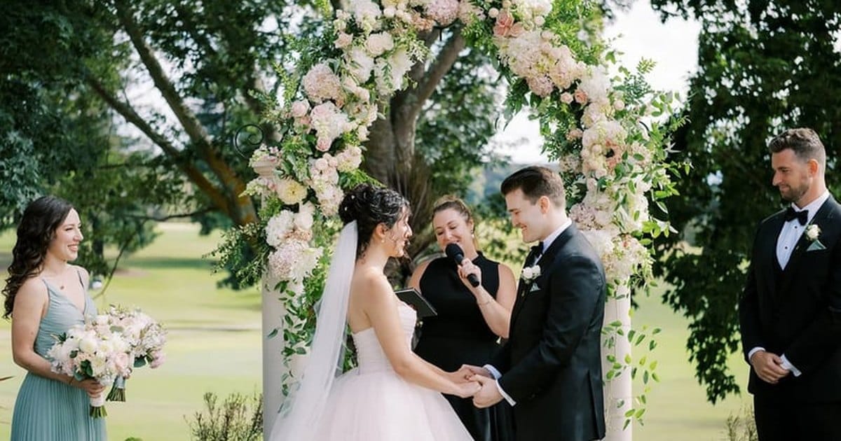 Officiant leading a small outdoor Bay Area wedding ceremony at a floral arch