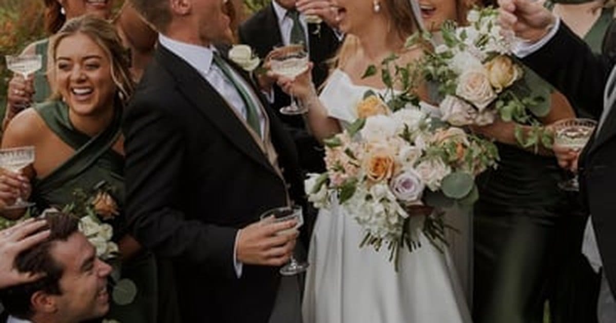 Bride holding a bouquet laughing with her wedding party as they raise coupe glasses outdoors, from a Walnut Creek day-of wedding coordinator