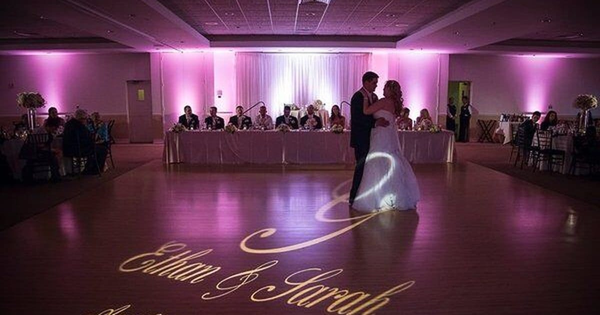 Couple's first dance under pink uplighting from a Bay Area wedding DJ package, names projected on the floor