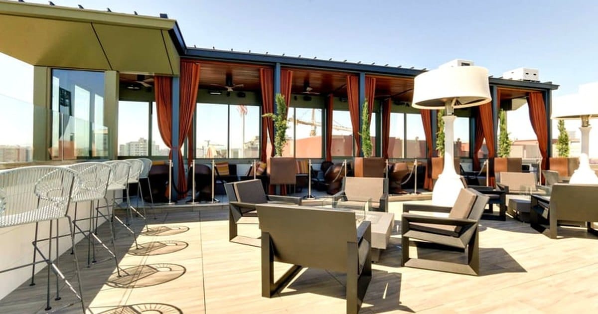 Sunny rooftop terrace with lounge chairs, a bar counter and a patio heater in South of Market