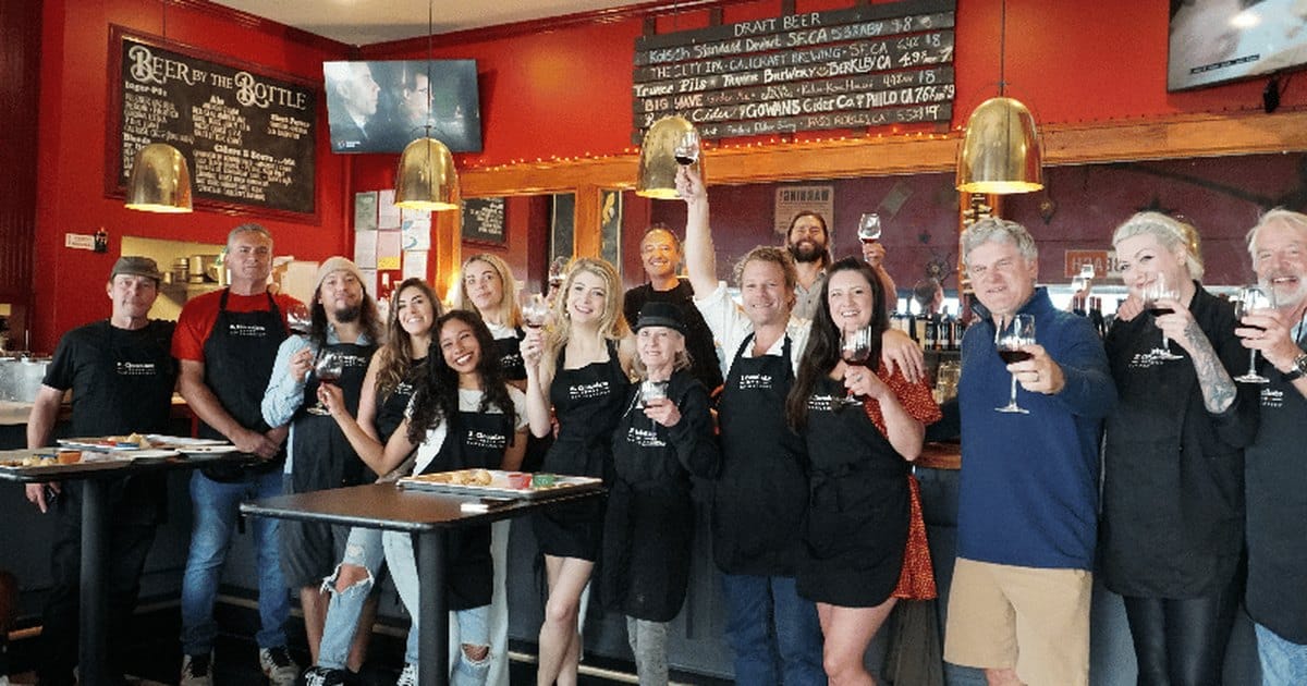 Group in aprons raising wine glasses in a San Francisco restaurant after a food and wine class
