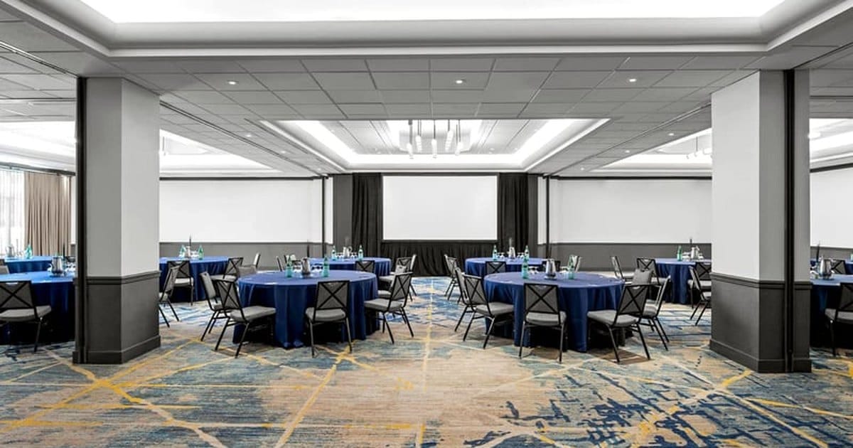 Santa Clara hotel meeting room set for a banquet, with round tables in navy linens and gray chairs