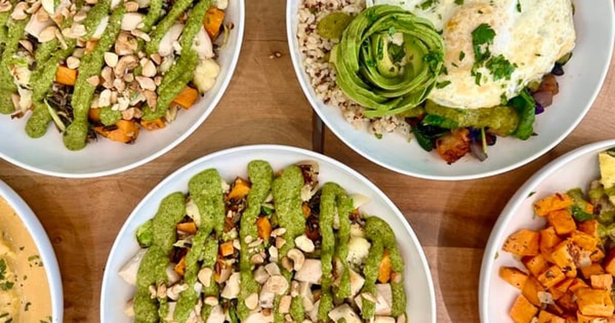 Plant based catering bowls of grains, roasted vegetables and green sauce from a San Rafael kitchen, laid out on a wooden table