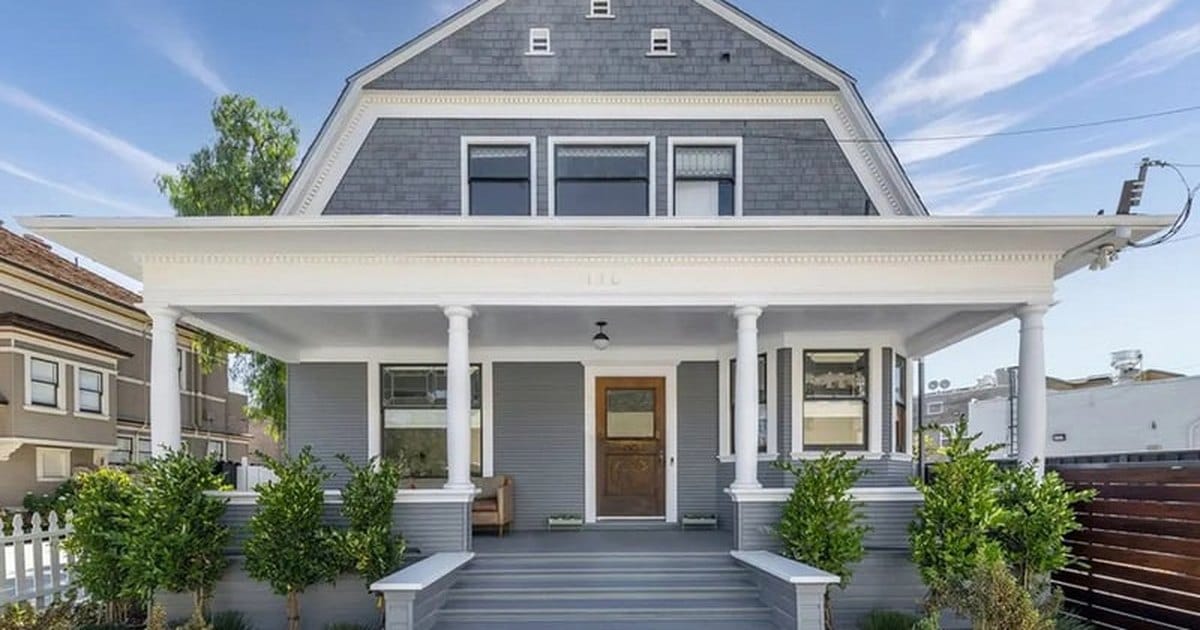 Gray Dutch Colonial estate venue in Redwood City with a gambrel roof, white columns and a wide front porch under a blue sky