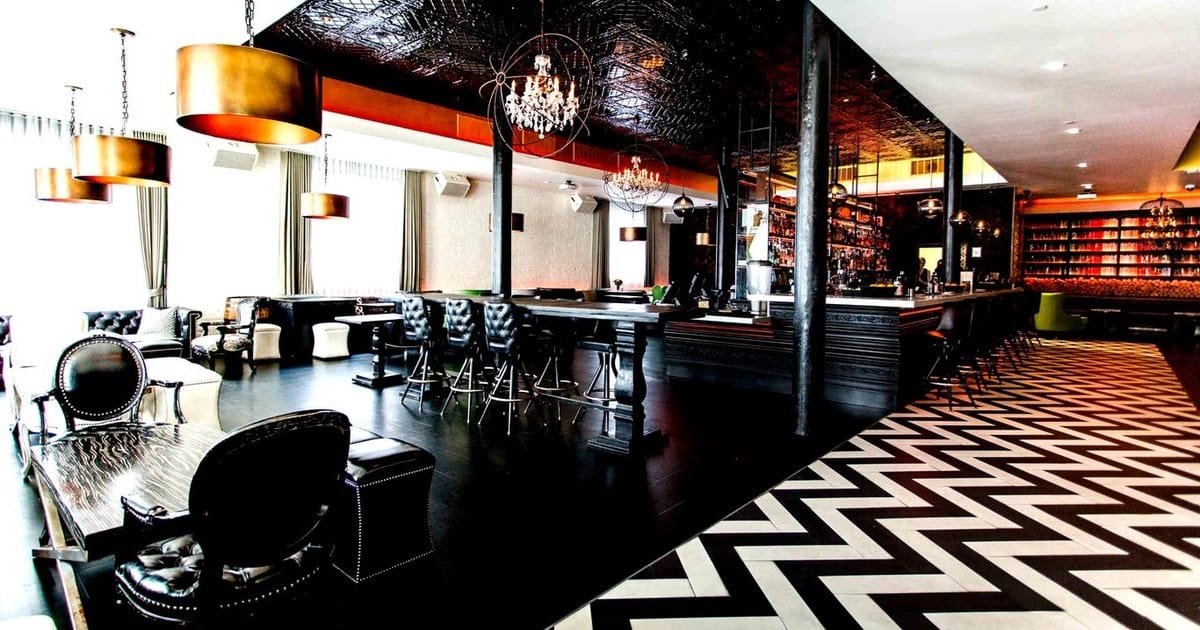 South Beach bar and lounge in San Francisco with chandeliers, leather chairs, a long bar and a black and white chevron floor