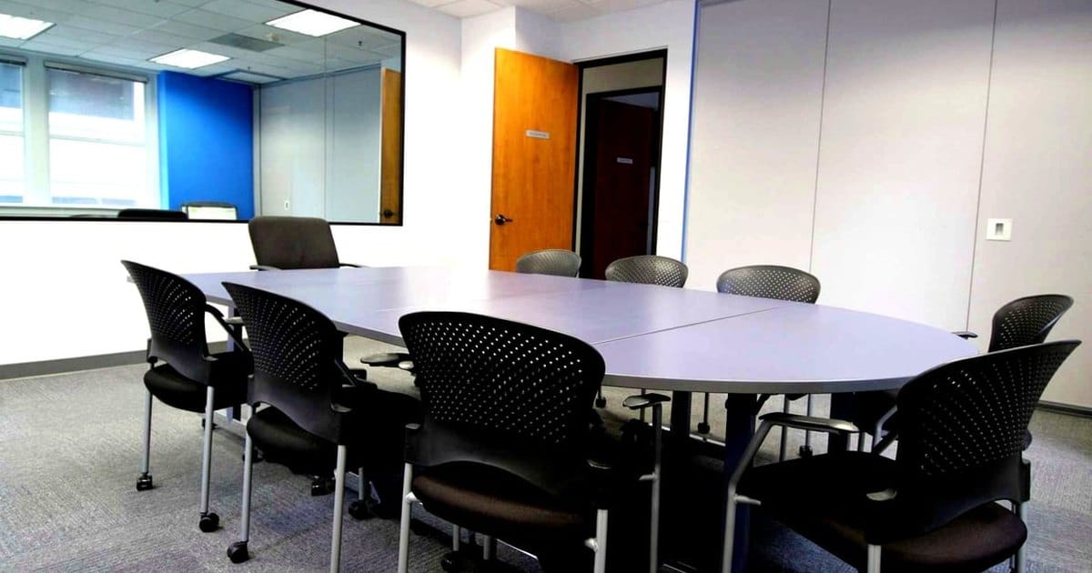 Financial District conference room in San Francisco with a long oval table, black mesh chairs and an interior window