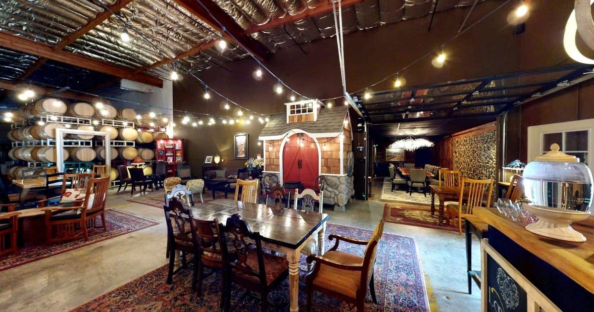 Barrel room at a Livermore winery event space with string lights, rugs and wooden dining tables