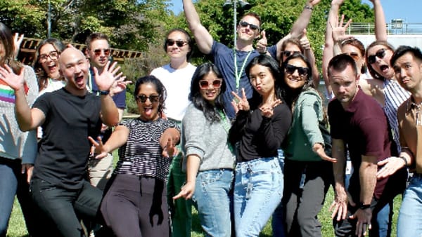 A large corporate team laughing and posing together outdoors during a team building game