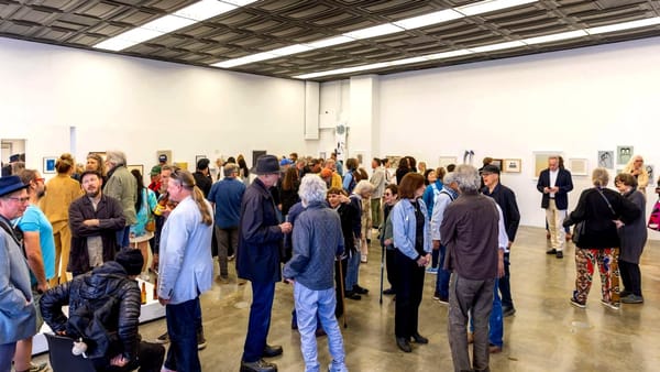 Guests mingling at a crowded evening reception inside a white-walled gallery venue on San Francisco's northern waterfront