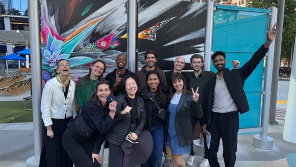 A corporate team celebrating at the finish of a San Francisco scavenger hunt in front of a mural