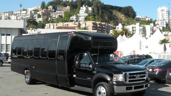 Black executive limo bus parked in San Francisco with Telegraph Hill houses behind it