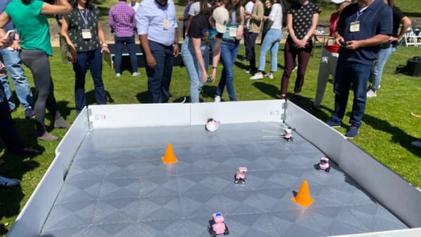 Biotech professionals gathered around a robotics arena during a team-building activity
