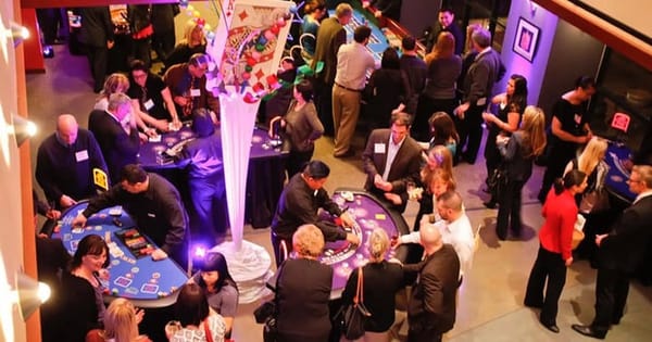 Guests playing at several casino night tables at a Bay Area company party under purple lighting