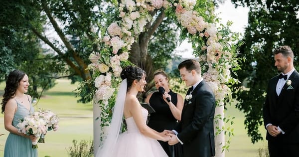Officiant leading a small outdoor Bay Area wedding ceremony at a floral arch