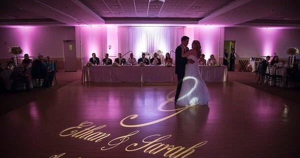 Couple's first dance under pink uplighting from a Bay Area wedding DJ package, names projected on the floor