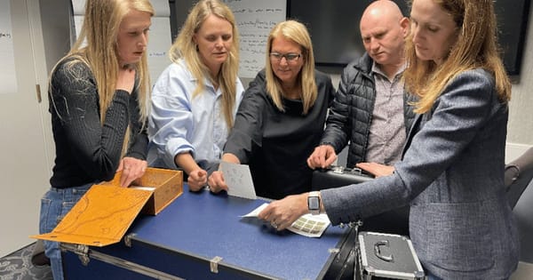 Team gathered around a locked puzzle case during a mobile escape room event