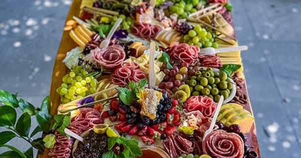 Long flat lay grazing table with salami roses, grapes, cheeses and olives on a covered Bay Area patio