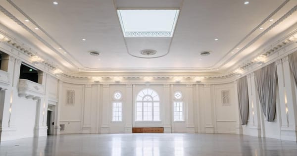 Empty white ballroom in San Francisco with arched windows, a skylight and a polished floor