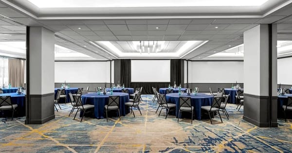 Santa Clara hotel meeting room set for a banquet, with round tables in navy linens and gray chairs