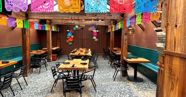 Private dining room on Union Street in San Francisco with wooden tables, black chairs and colorful paper banners overhead
