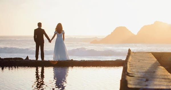 Wedding couple at the edge of a still coastal pool at sunset, from a San Francisco photo and video package listing