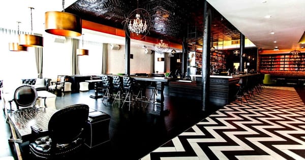 South Beach bar and lounge in San Francisco with chandeliers, leather chairs, a long bar and a black and white chevron floor