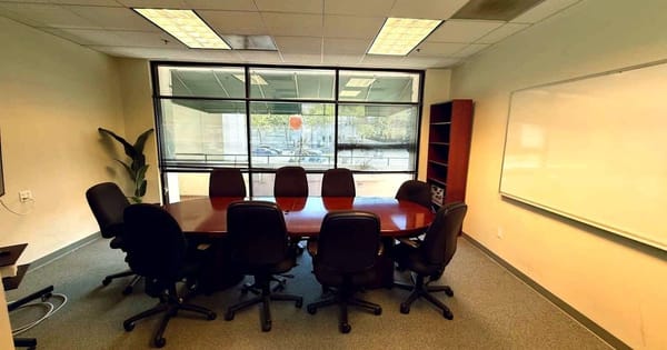 Menlo Park meeting room with an oval conference table, black office chairs, a whiteboard and a large street-facing window